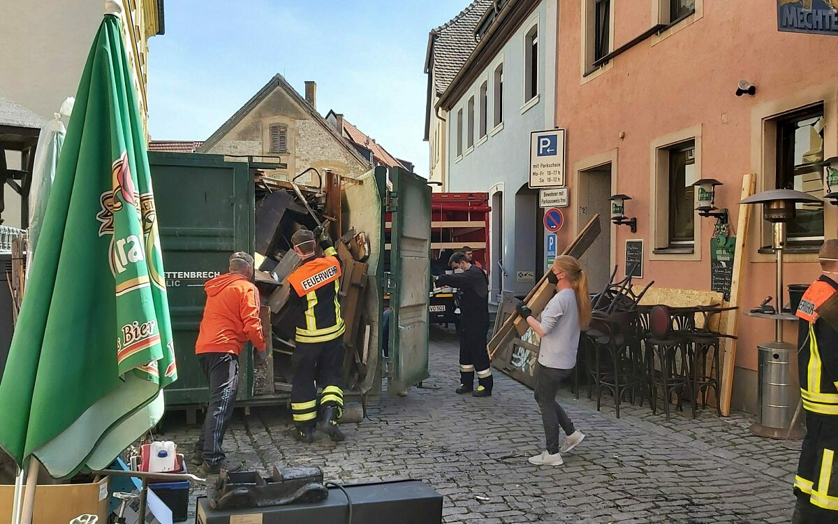 Helfer werfen verbranntes inventar in container Helfer werfen verbranntes inventar in container