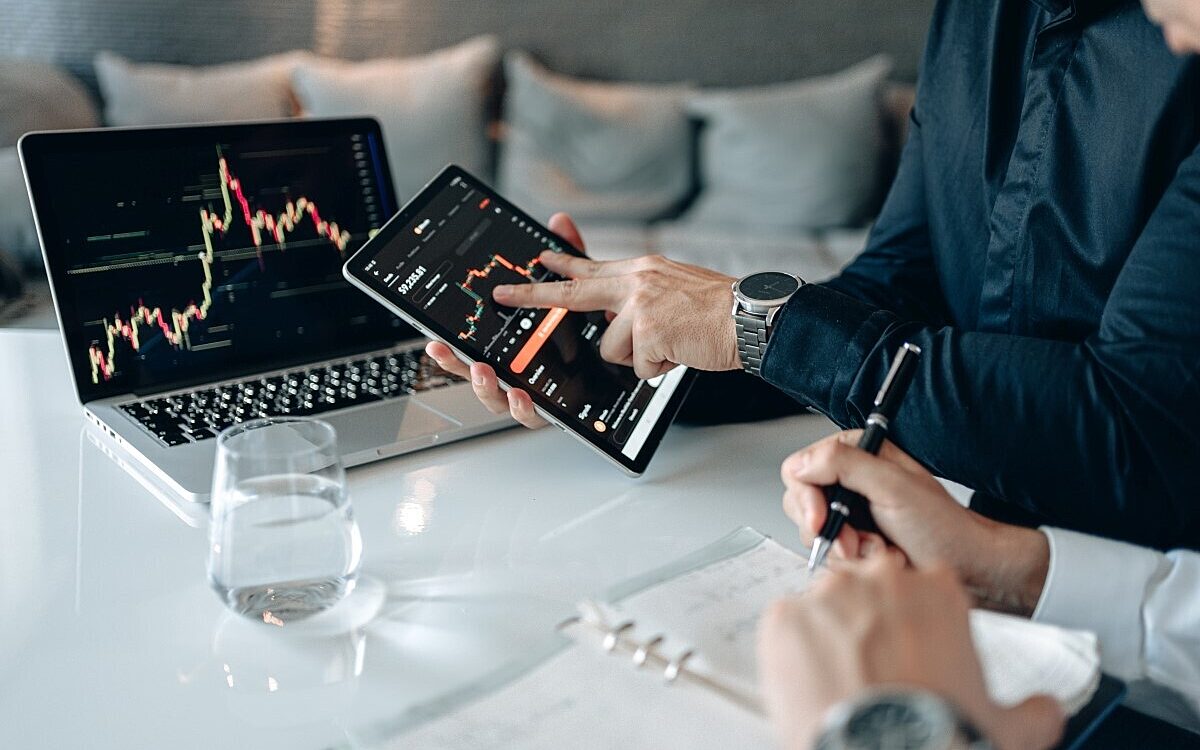 Man in blue dress shirt holding black digital tablet beside a person writing Man in blue dress shirt holding black digital tablet beside a person writing