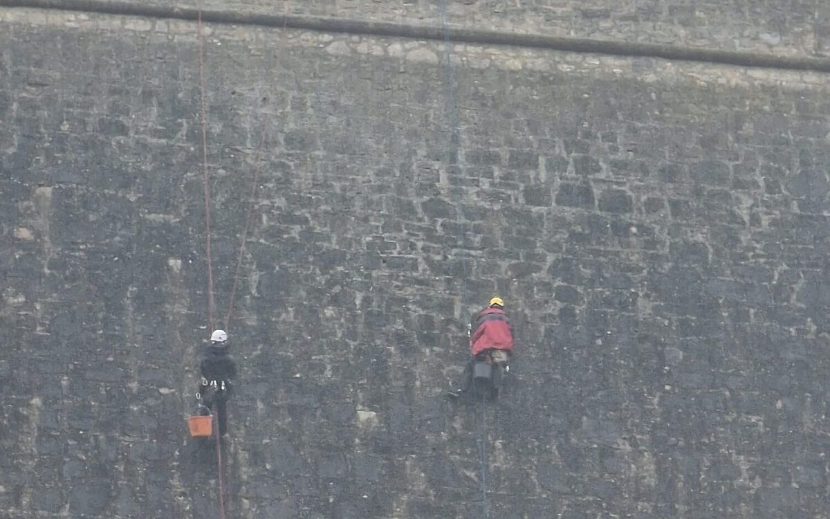 Arbeiter klettern an der Festungsmauer entlang Arbeiter klettern an der Festungsmauer entlang