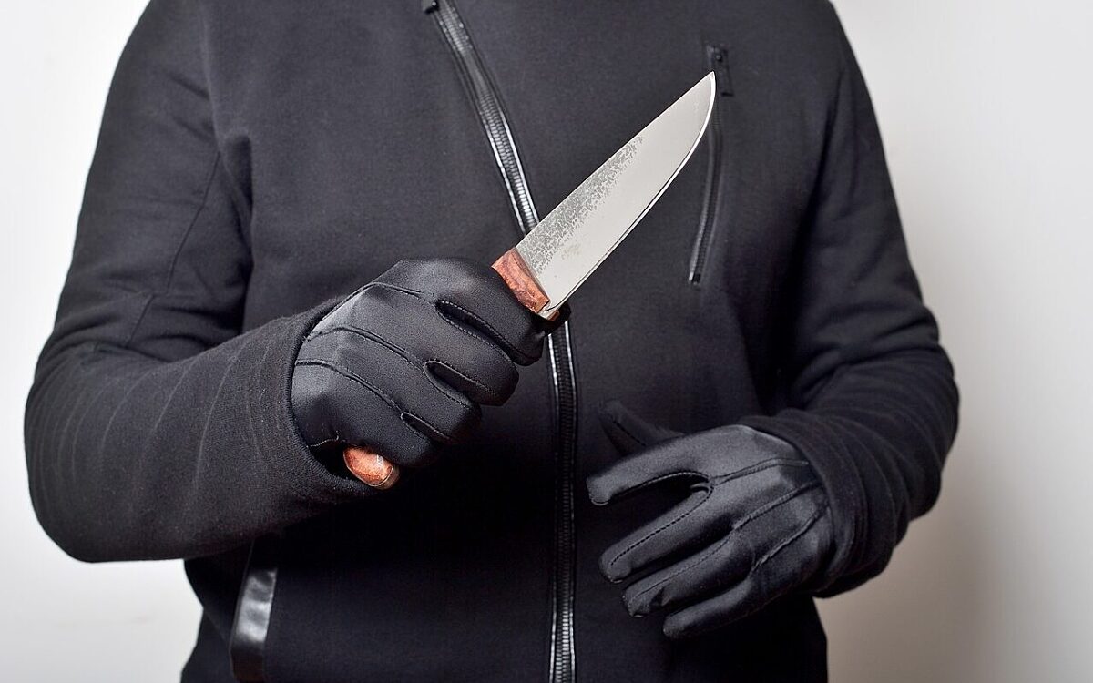 Ein Mann mit schwarzen Handschuhen und einem Messer in der Hand Ein Mann mit schwarzen Handschuhen und einem Messer in der Hand
