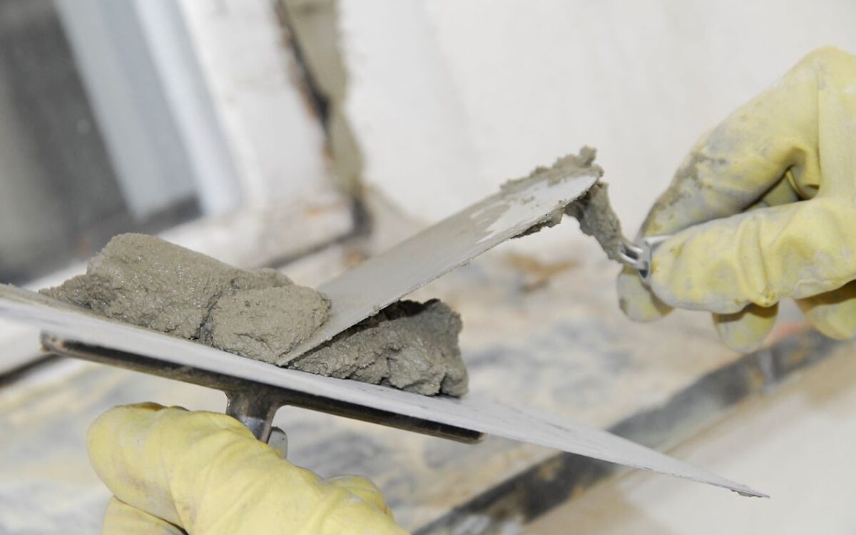 Kelle in Maurerhand auf einer Baustelle Kelle in Maurerhand auf einer Baustelle