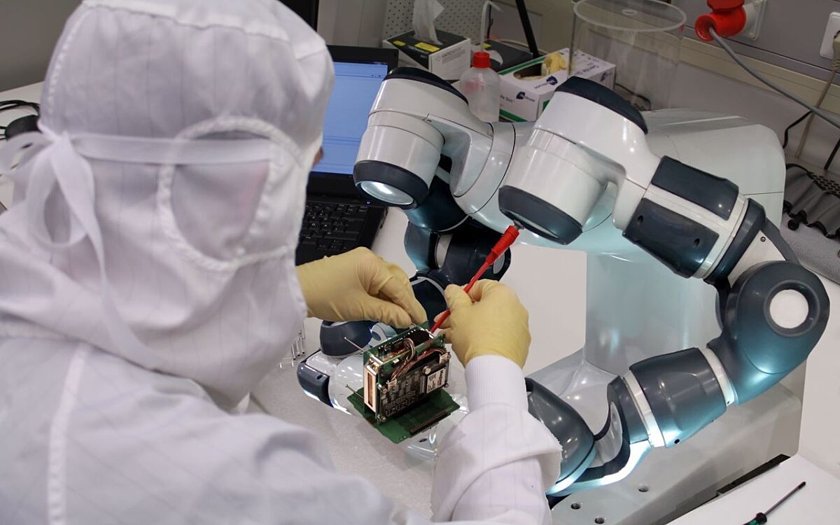 Ein Mensch und ein Roboter bauen mini-Satelliten Ein Mensch und ein Roboter bauen mini-Satelliten