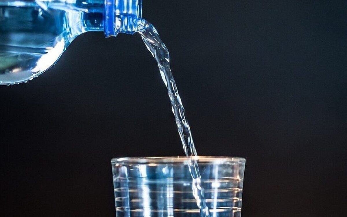 Mineralwasser wird eingeschenkt aus einer Flasche Wasser Mineralwasser wird eingeschenkt aus einer Flasche Wasser