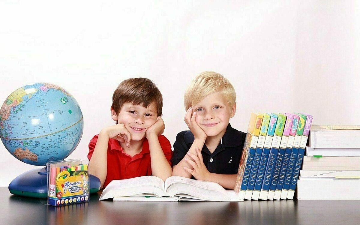 Schulkinder sitzen vor einem Buch Schulkinder sitzen vor einem Buch