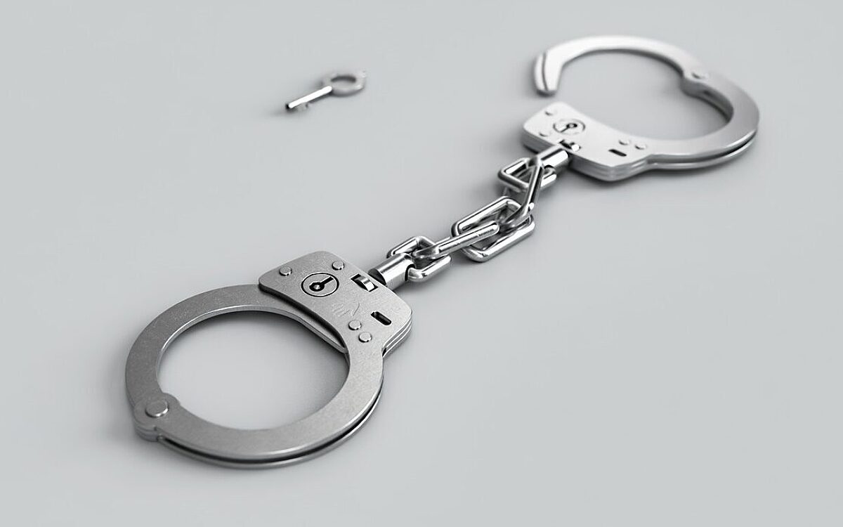 Silberne Handschellen vor einem weißen Hintergrund Silberne Handschellen vor einem weißen Hintergrund