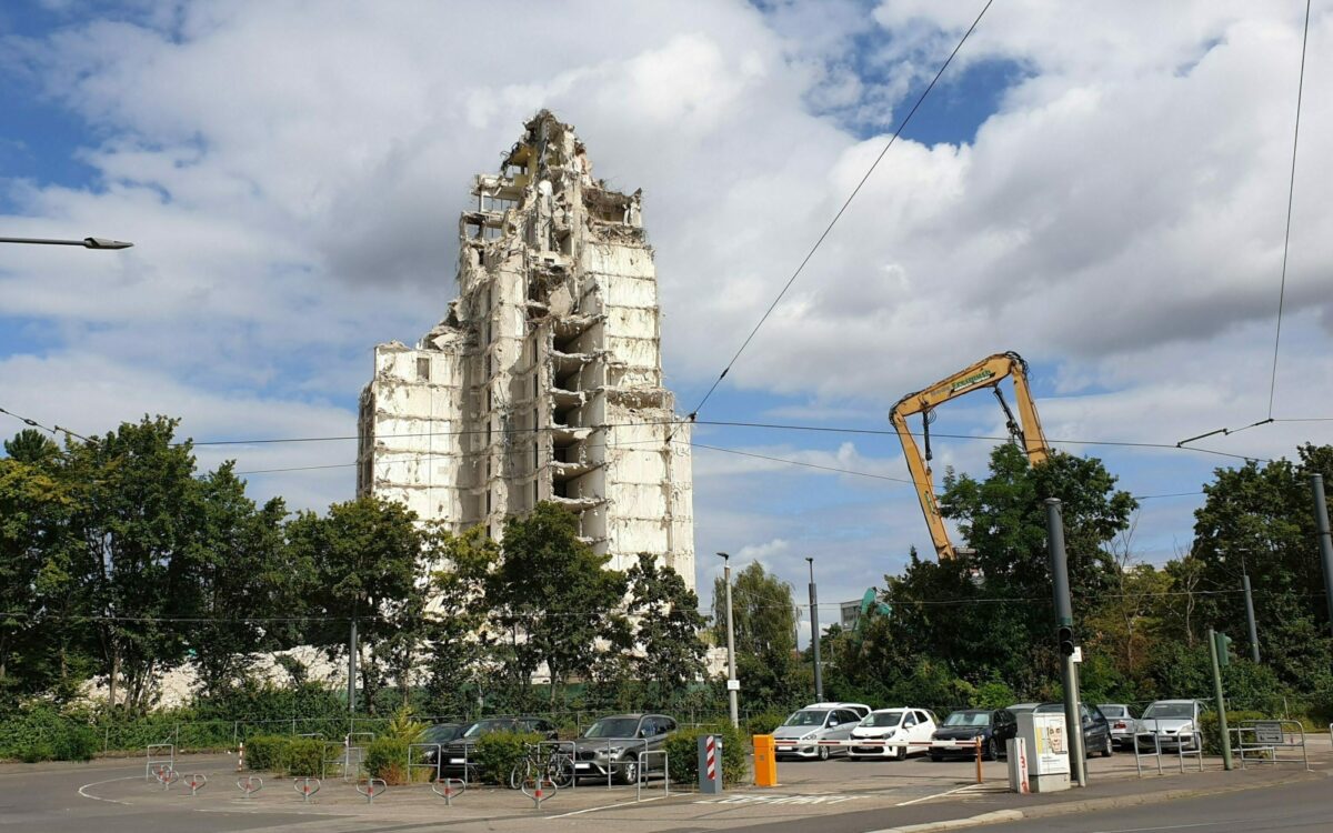 Ein großer Abrissbagger steht neben der Ruine des ehemaligen Hochhauses mit dem Dachcafe Ein großer Abrissbagger steht neben der Ruine des ehemaligen Hochhauses mit dem Dachcafe