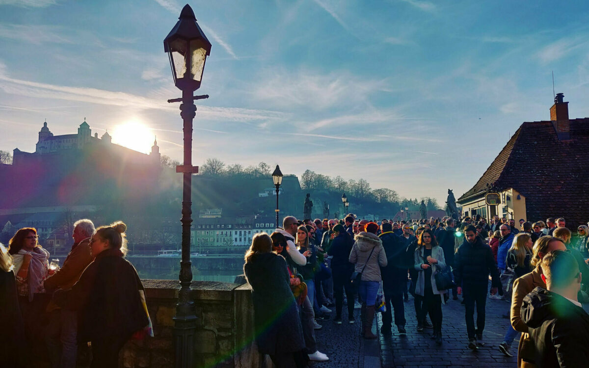 Menschen auf der Alten Mainbrücke in Würzburg bei Sonnenschein mit Blick auf die Festung Marienberg Menschen auf der Alten Mainbrücke in Würzburg bei Sonnenschein mit Blick auf die Festung Marienberg