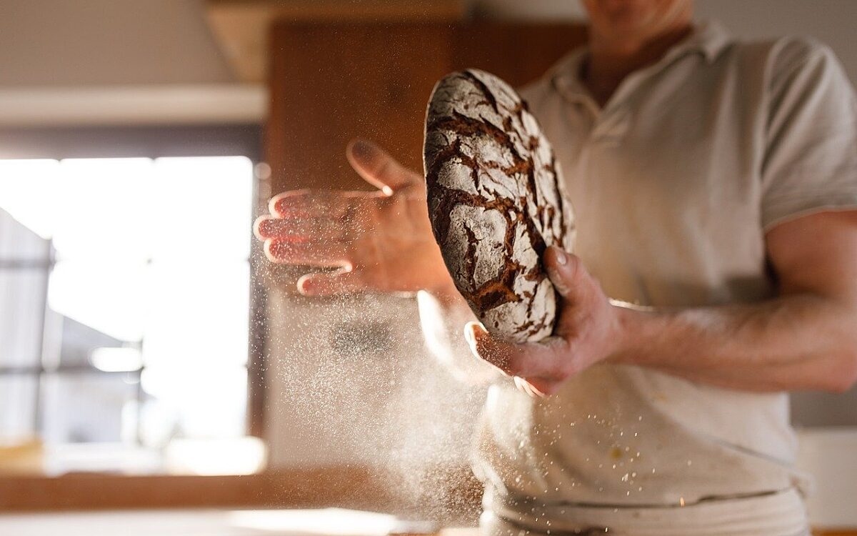 Ein Bäcker hält ein Brot in der Hand Ein Bäcker hält ein Brot in der Hand
