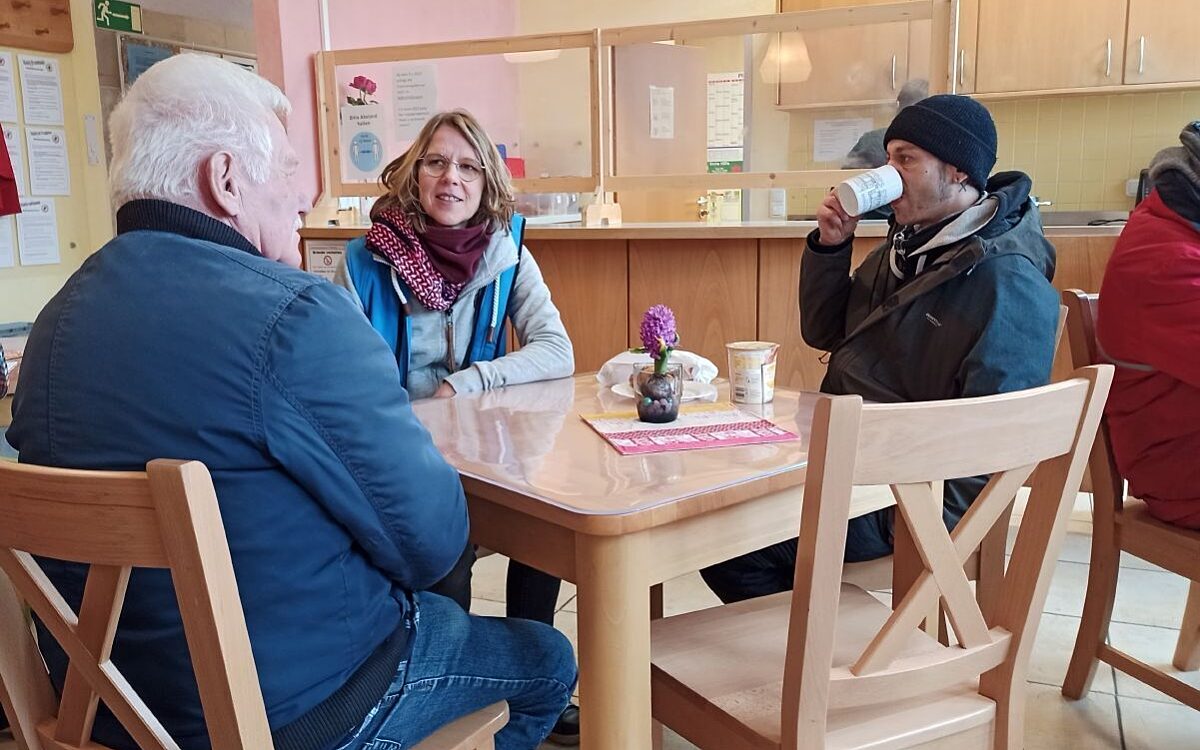 Menschen sitzen in der Würzburger Bahnhofsmission zusammen, trinken etwas Warmes und reden. Menschen sitzen in der Würzburger Bahnhofsmission zusammen, trinken etwas Warmes und reden.