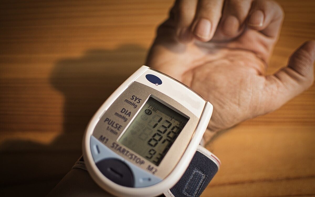 Eine Person misst den Blutdruck mit einem Gerät am Handgelenk Eine Person misst den Blutdruck mit einem Gerät am Handgelenk