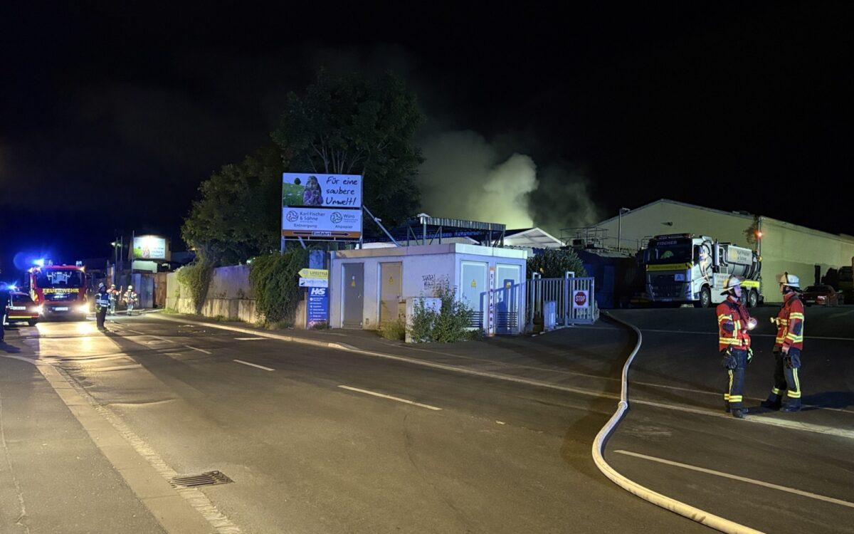 Feuerwehrleute stehen auf der Winterhäuser Straße. Im Hintergrund steigt Rauch auf Feuerwehrleute stehen auf der Winterhäuser Straße. Im Hintergrund steigt Rauch auf