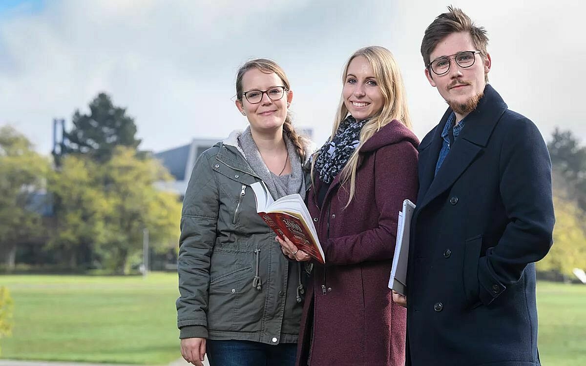 Drei studenten mit einem buch auf dem campus der uni 2021 07 20 151058 vihj Drei studenten mit einem buch auf dem campus der uni 2021 07 20 151058 vihj