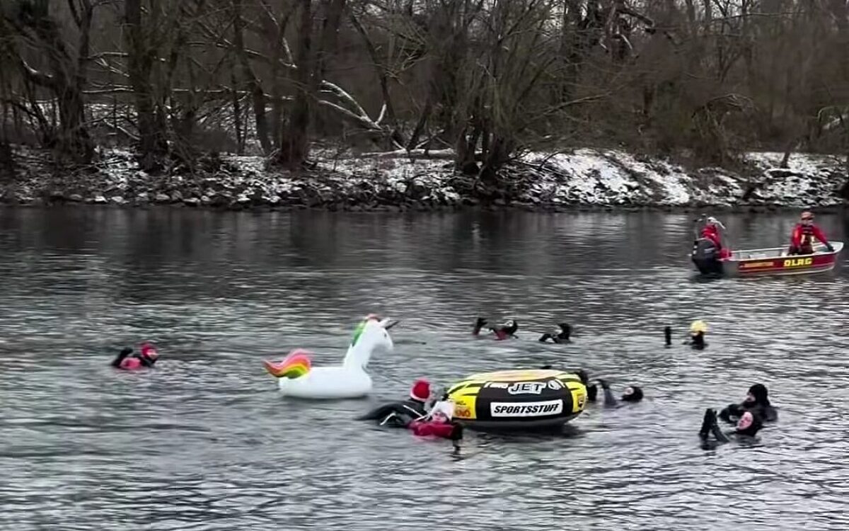 Begleitet von einem Boot der DLRG befinden sich Schwimmer im eiskalten Main