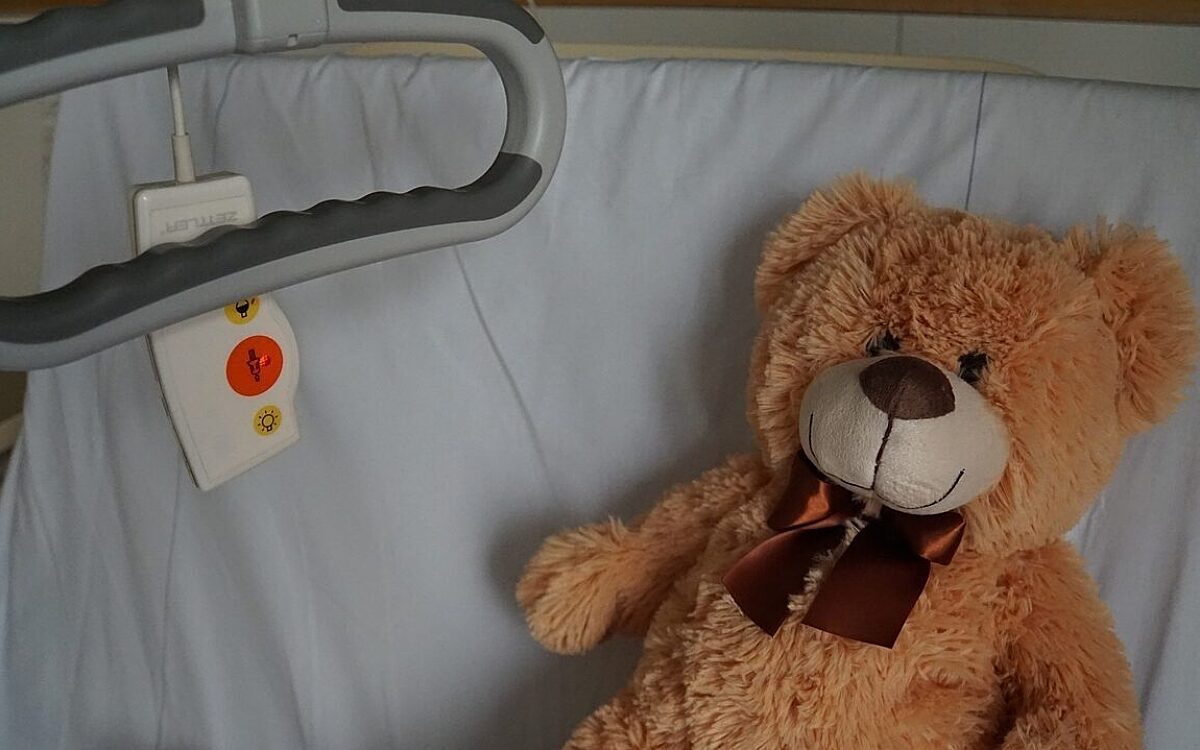 Ein Teddy in einem Krankenbett in einem Krankenhaus fuer Kinder Ein Teddy in einem Krankenbett in einem Krankenhaus fuer Kinder