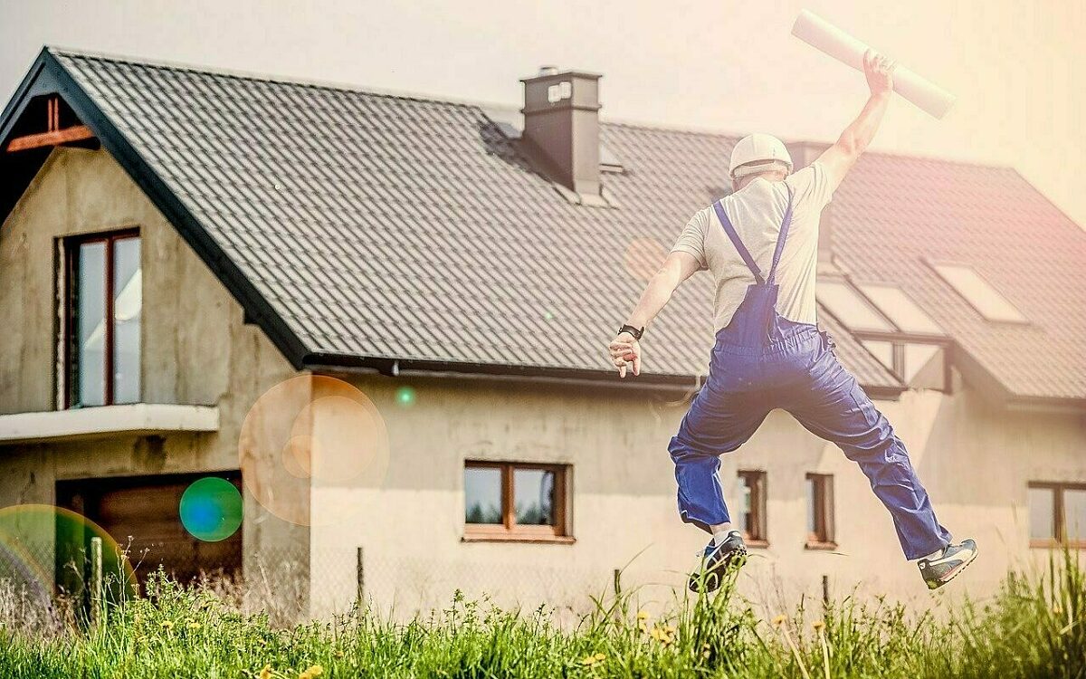 Ein Bauarbeiter springt vor einem Neubau in die Luft Ein Bauarbeiter springt vor einem Neubau in die Luft