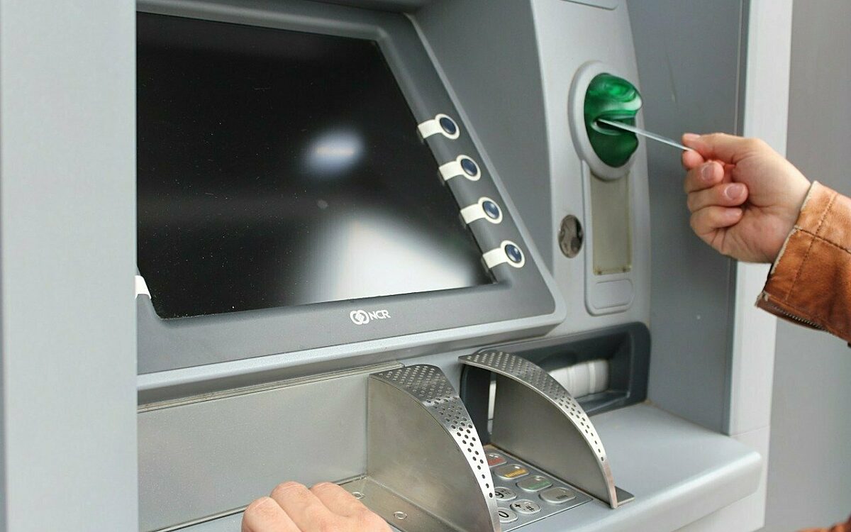 Jemand hebt Geld am Bankautomaten ab Jemand hebt Geld am Bankautomaten ab