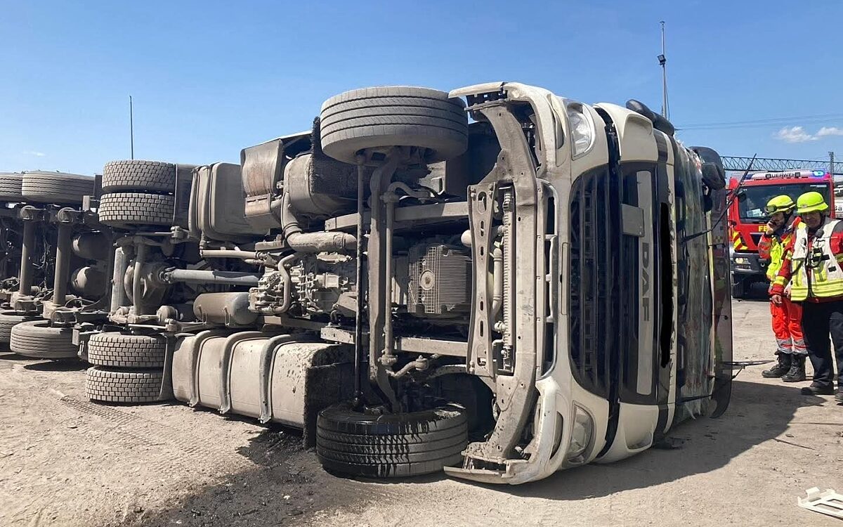 Der umgestürzte Laster liegt auf einem Firmengelände auf der Seite Der umgestürzte Laster liegt auf einem Firmengelände auf der Seite