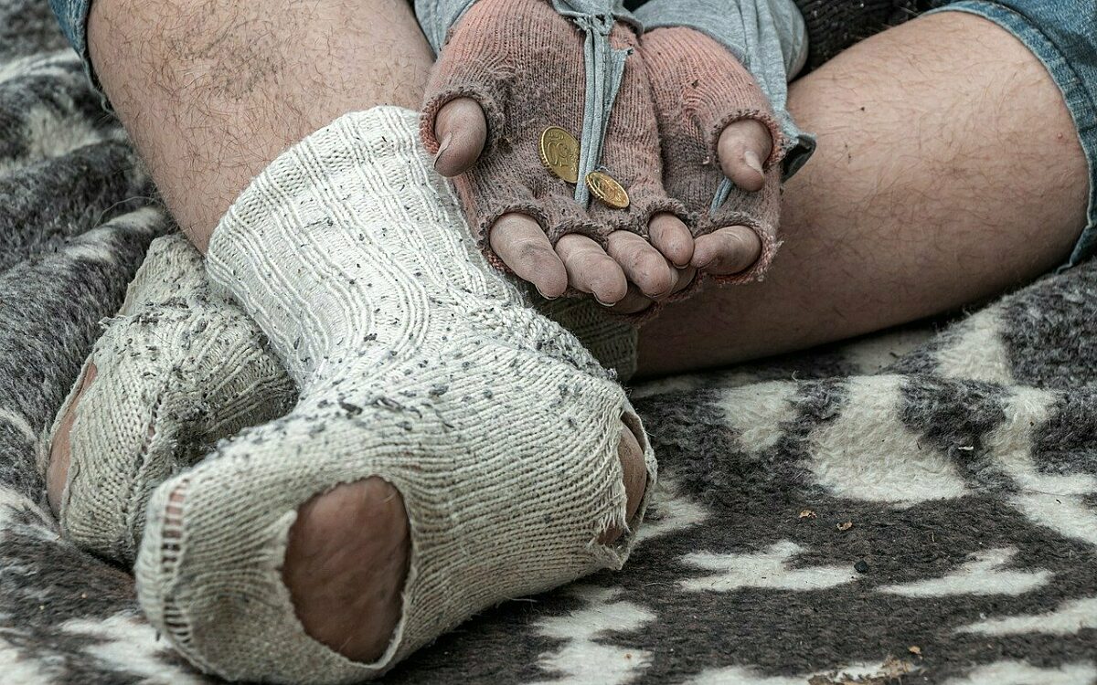 Ein obdachloser Mensch bettelt auf einer Decke Ein obdachloser Mensch bettelt auf einer Decke