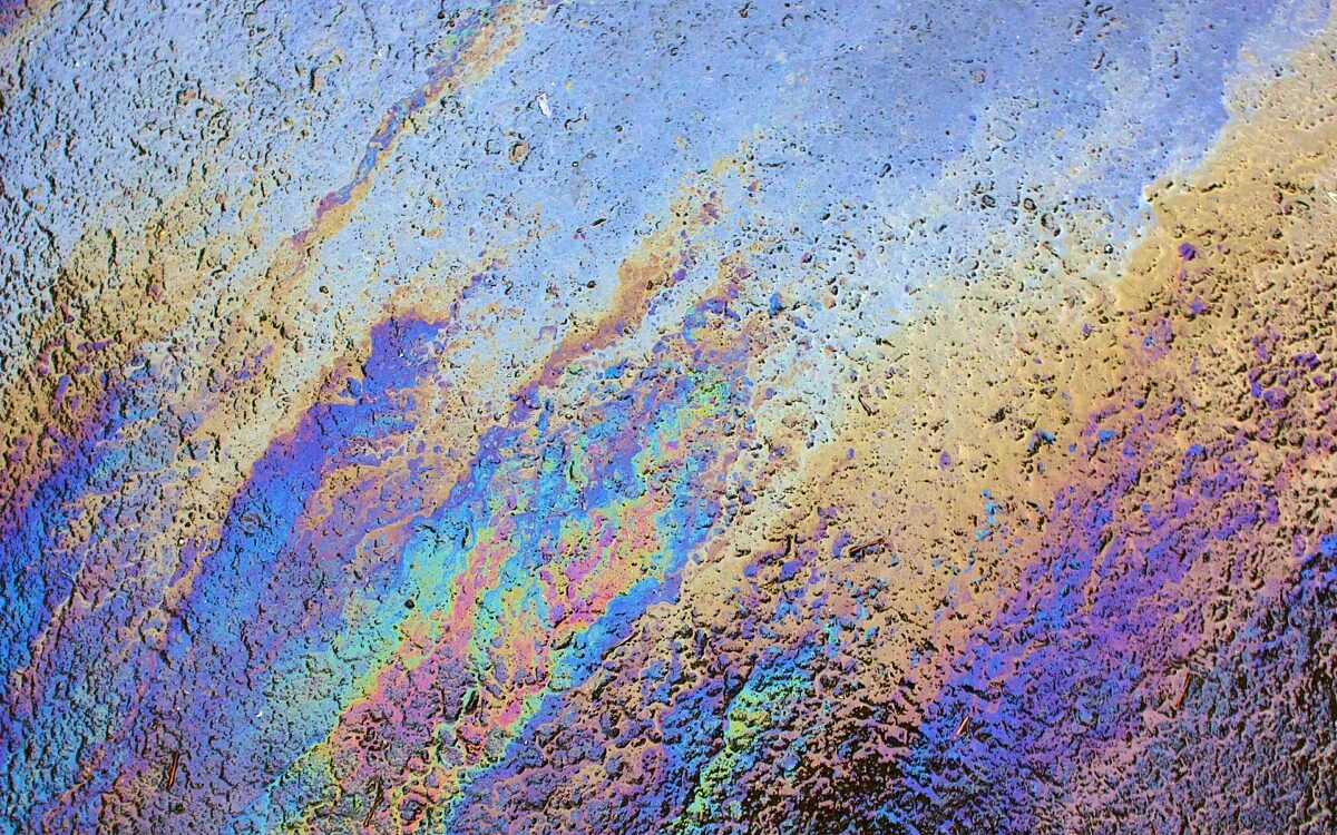Eine Öl-Lache schimmert in Regenbogenfarben Eine Öl-Lache schimmert in Regenbogenfarben