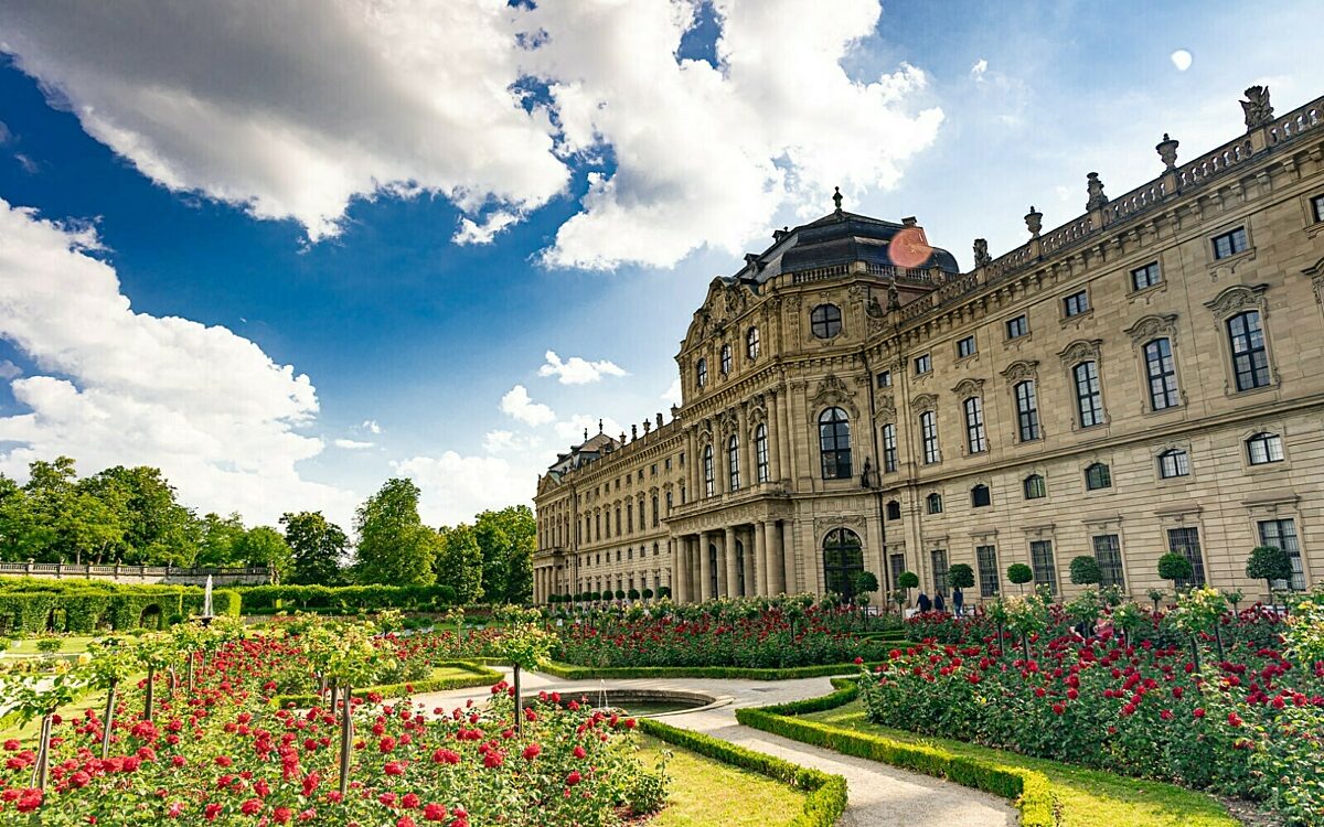 Residenz Würzburg seitlicher Blick vom Residenzgartenmit Blumen und Wolken sowie Sonnenschein Residenz Würzburg seitlicher Blick vom Residenzgartenmit Blumen und Wolken sowie Sonnenschein