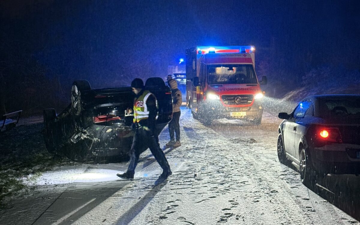Nach einem Unfall auf schneebedeckter Fahrbahn liegt ein PKW auf dem Dach