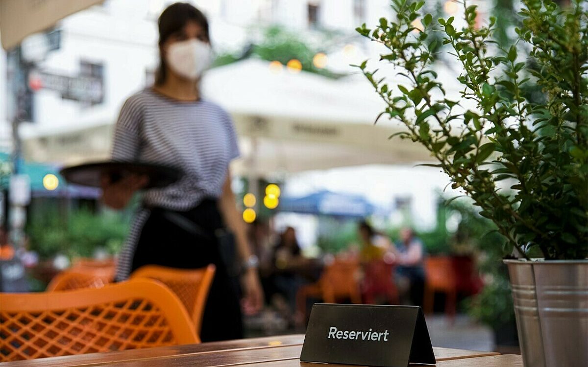 Eine Servicekraft steht hinter einem reservierten Tisch Eine Servicekraft steht hinter einem reservierten Tisch