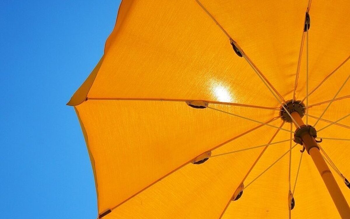 Die Sonne scheint durch einen Sonnenschirm Die Sonne scheint durch einen Sonnenschirm