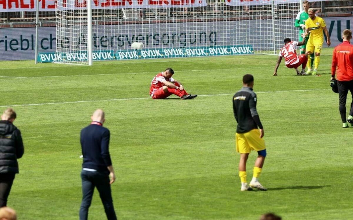Spieler der wuerzburger kickers nach abstieg sitzend auf spielfeld Spieler der wuerzburger kickers nach abstieg sitzend auf spielfeld