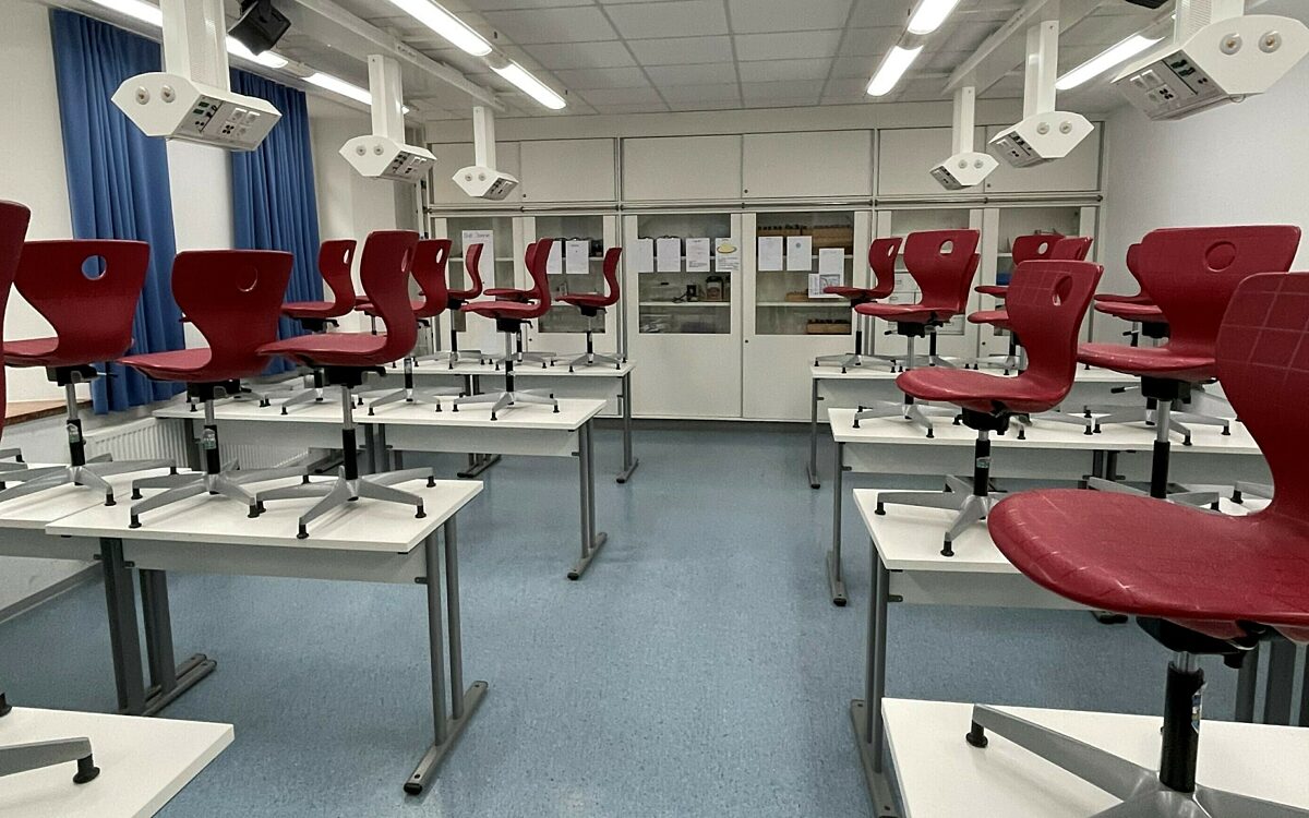 Rote Stühle stehen auf den Tischen in einem Klassenzimmer einer Schule Rote Stühle stehen auf den Tischen in einem Klassenzimmer einer Schule