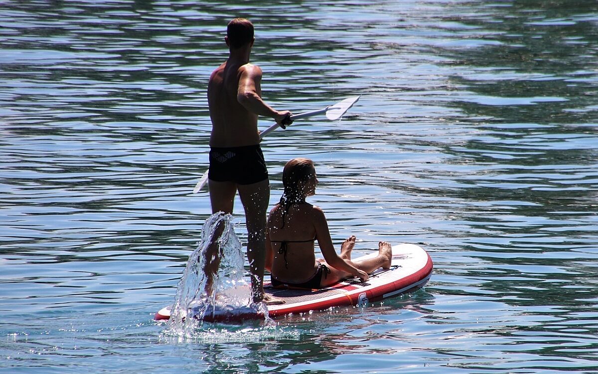 Ein Mann und eine Frau stehen bzw sitzen auf einem Stand up Paddle Bord Ein Mann und eine Frau stehen bzw sitzen auf einem Stand up Paddle Bord