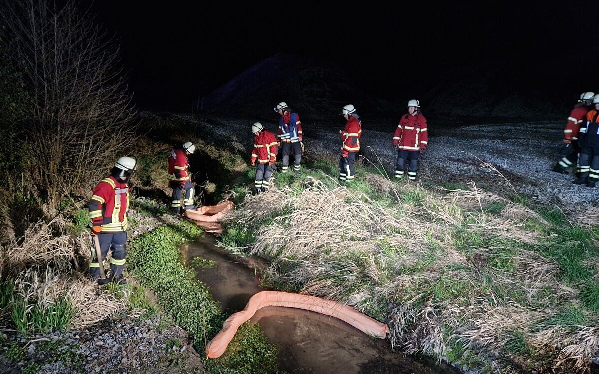 Die Feuerwehr sichert einen Bach gegen Öl mit einer Ölsperre Die Feuerwehr sichert einen Bach gegen Öl mit einer Ölsperre