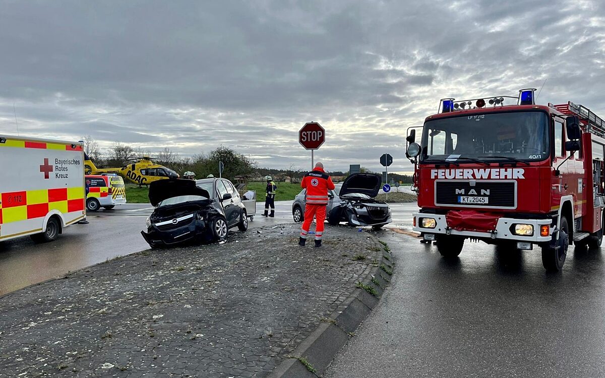 Zwei kaputte Autos stehen nach einem Unfall auf einer Kreuzung. Feuerwehr und Rettungswagen sind da. Zwei kaputte Autos stehen nach einem Unfall auf einer Kreuzung. Feuerwehr und Rettungswagen sind da.