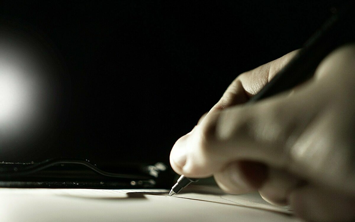 Eine Hand hält einen Kugelschreiber und unterschreibt auf einem Papier Eine Hand hält einen Kugelschreiber und unterschreibt auf einem Papier