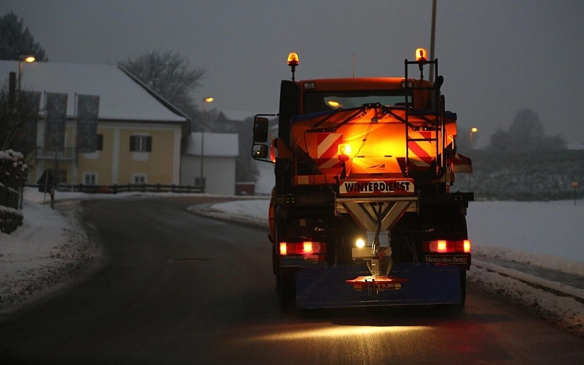 Der Winterdienst fährt in der Dämmerung auf einer eisigen Straße