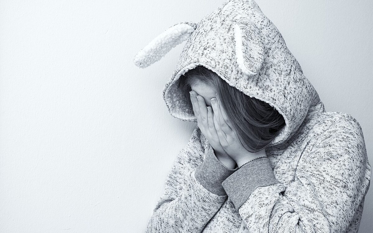 Ein Mädchen hält sich die Hände vors Gesicht Ein Mädchen hält sich die Hände vors Gesicht